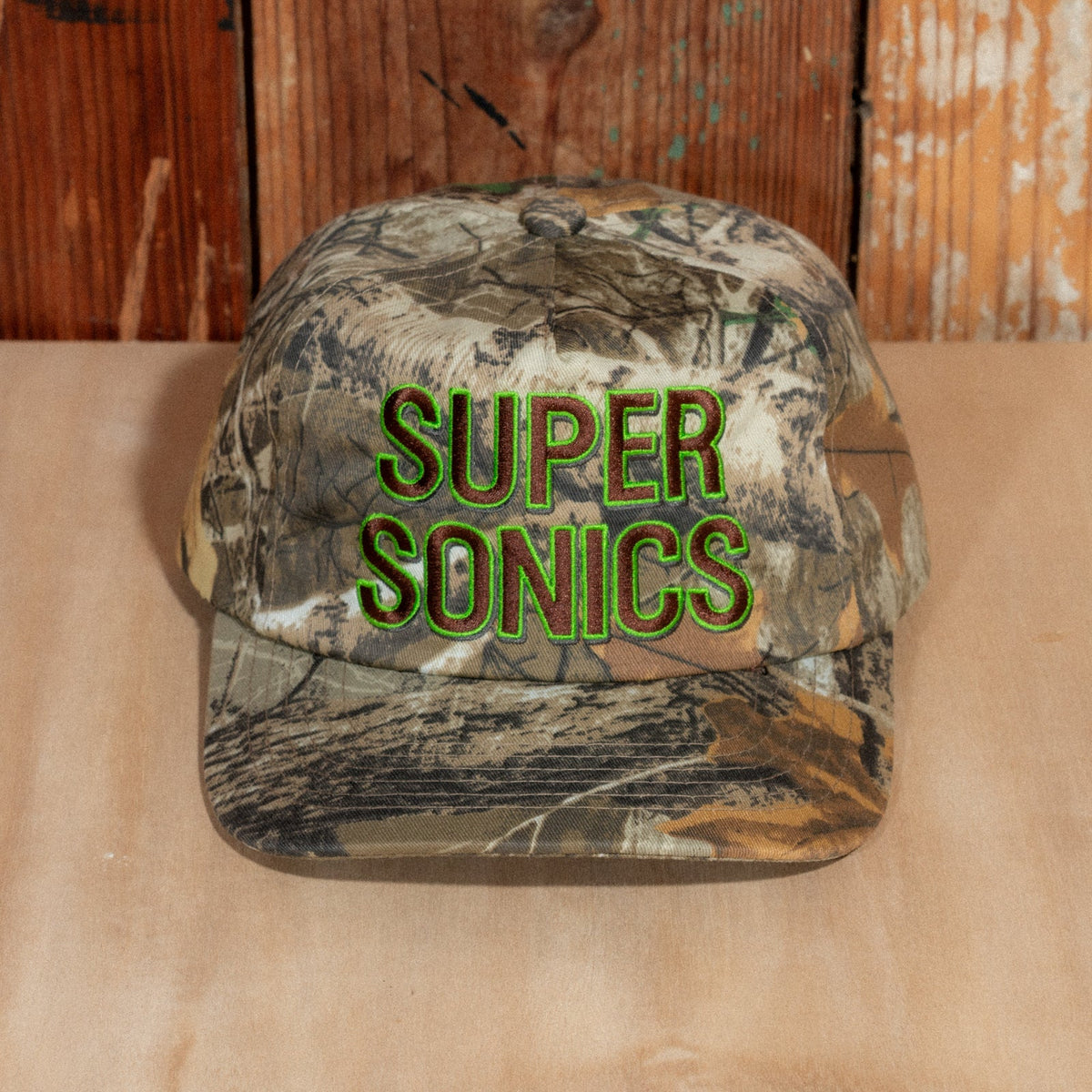 Close front view of the raised Super Sonics embroidery, brown lettering outlined in bright green