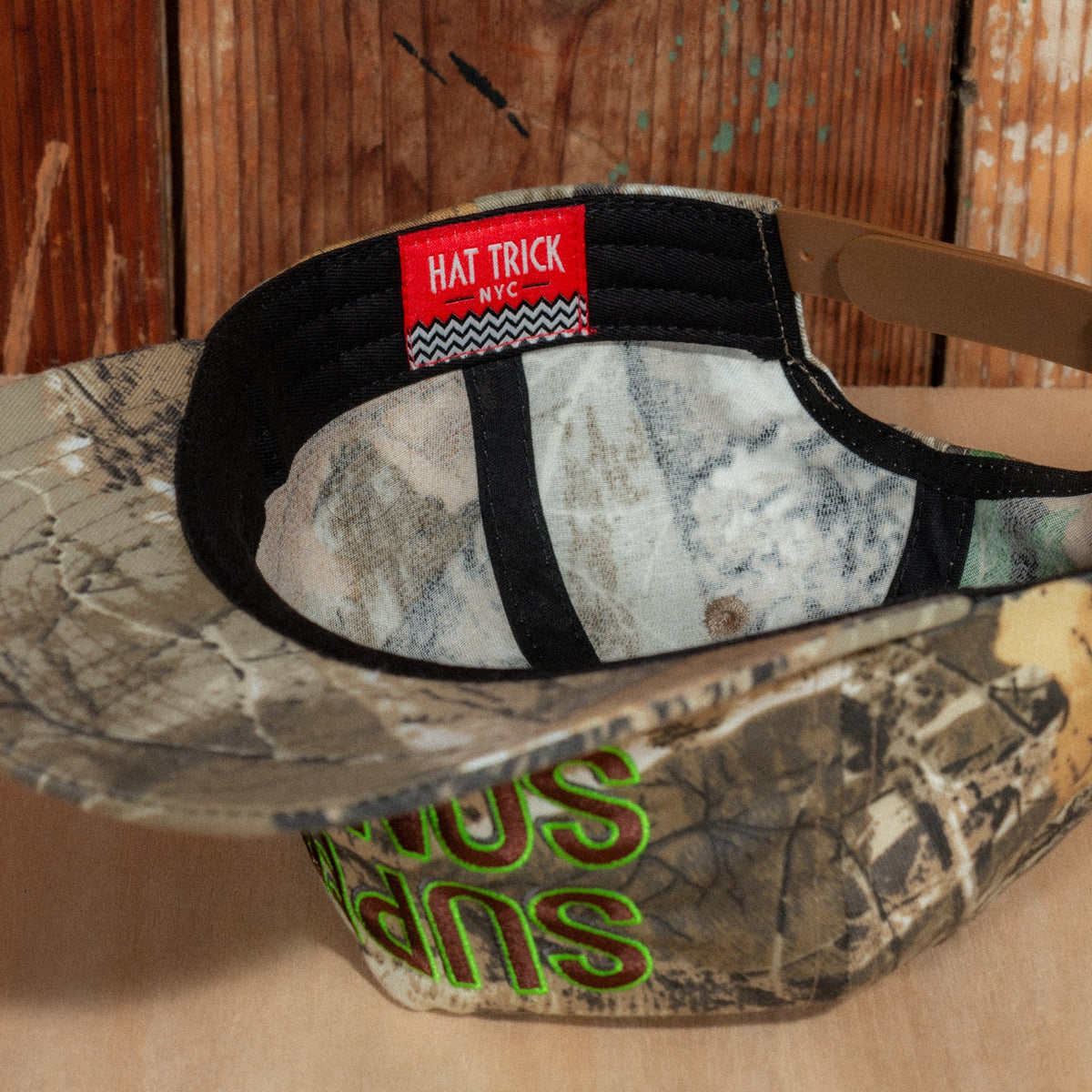 Underside of the brim showing the black sweatband and red Hat Trick NYC label with a zigzag stripe