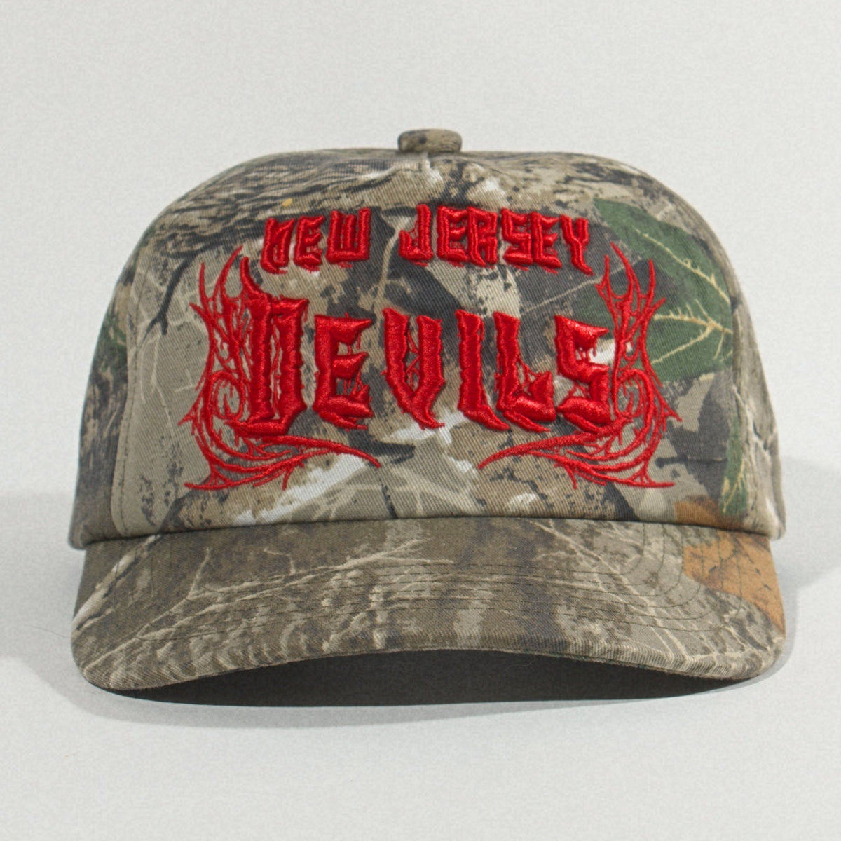Front view of the camo Devils hat centered on a plain gray backdrop