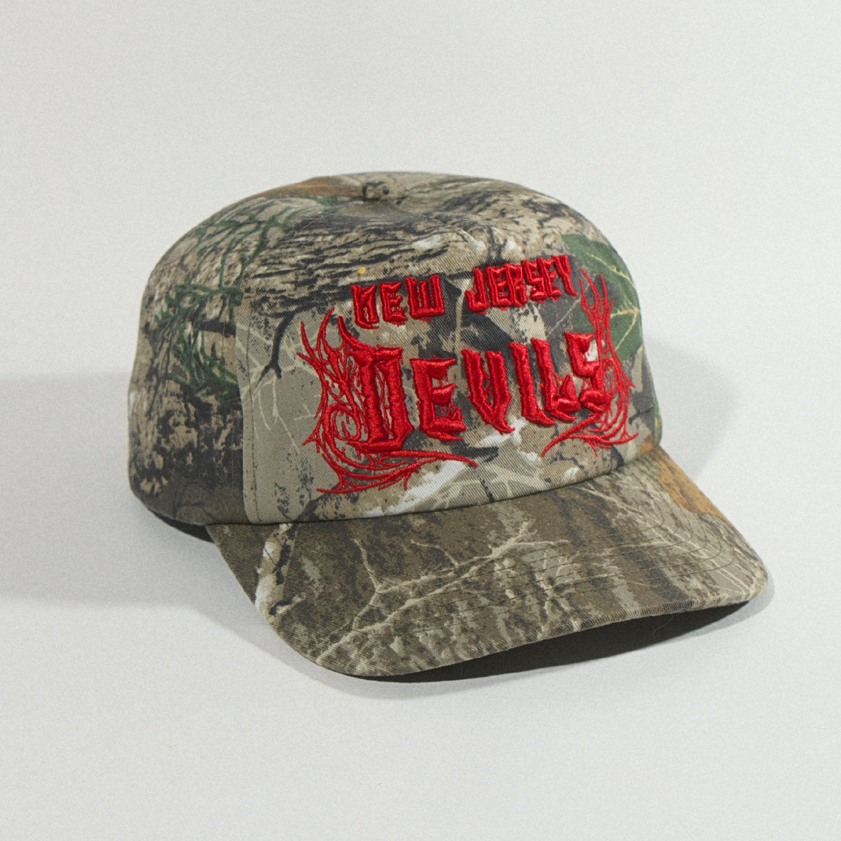 Three-quarter view from the right of the unstructured camo five-panel with raised red lettering