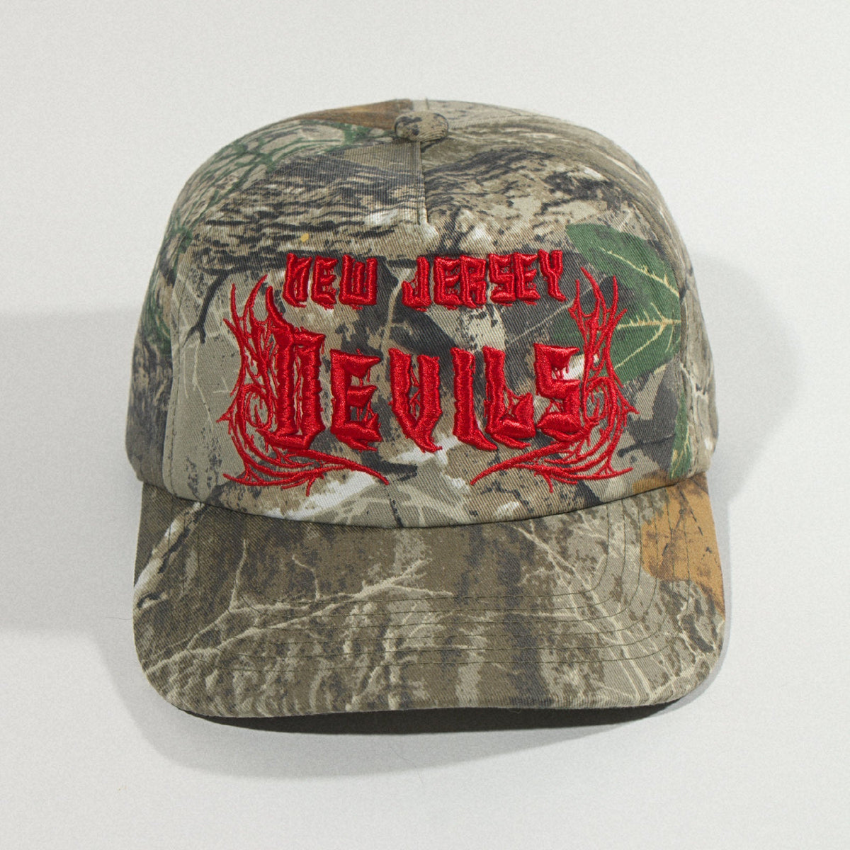 Front view from slightly above showing the full camo brim under the red lettering