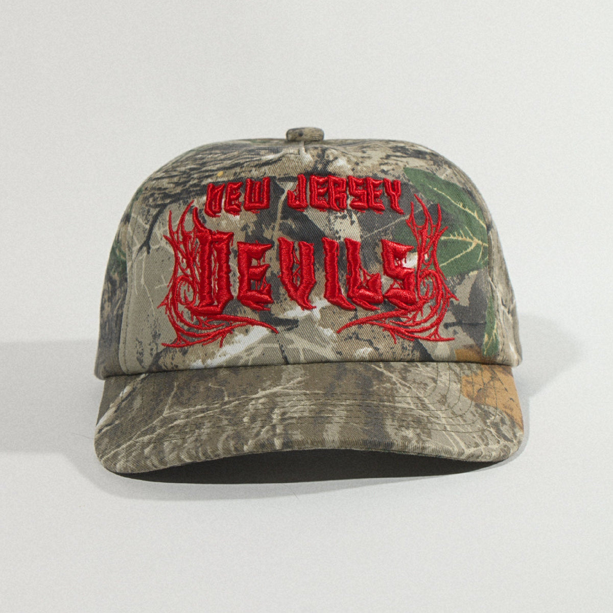 Front view of the hat sitting low on a gray backdrop, brim toward the camera