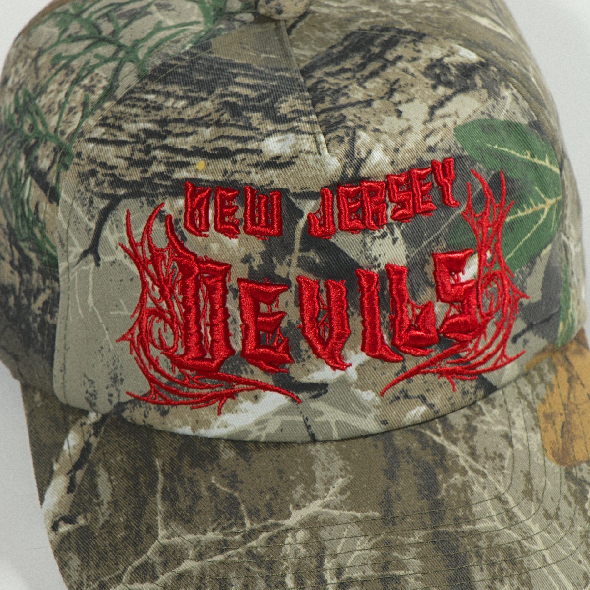 High close view of the crown button, camo panels and red Devils logo