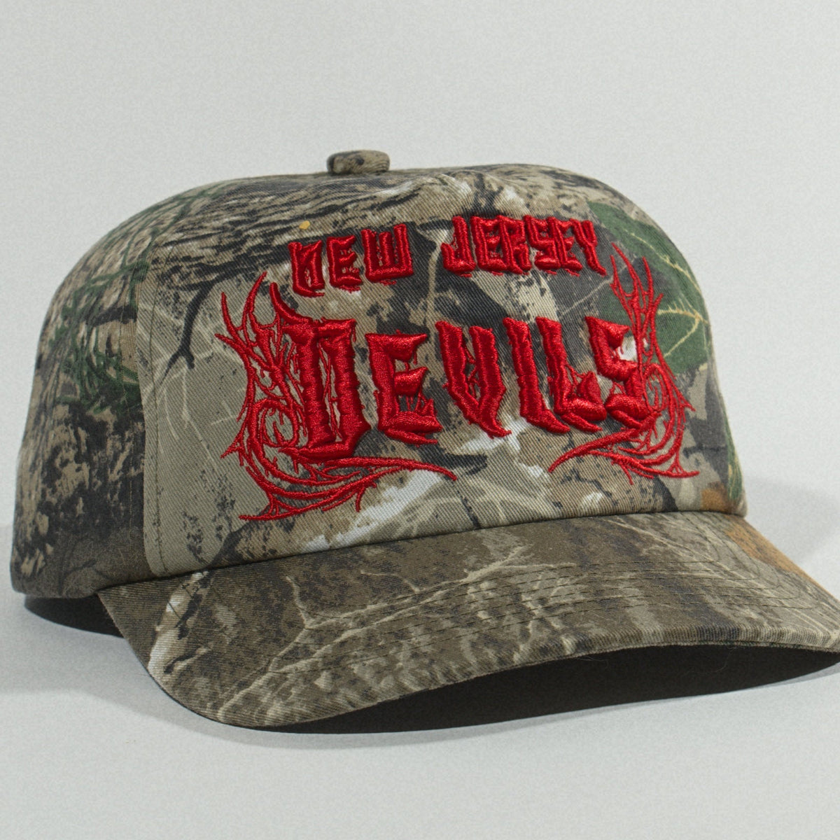Three-quarter view from the right with the camo brim angled toward the camera